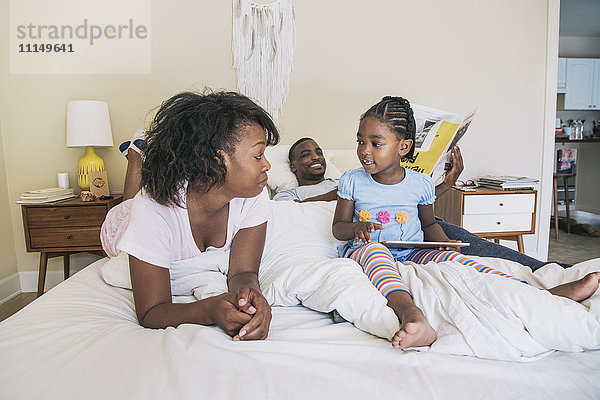 Afroamerikanische Eltern und Tochter auf dem Bett