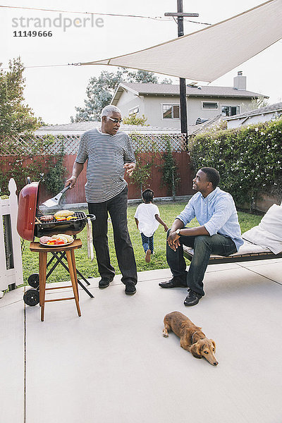 Afroamerikanischer Vater und Sohn unterhalten sich beim Grillen