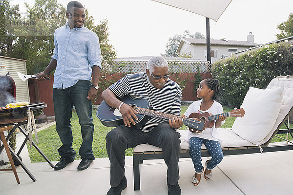 Afroamerikanischer Großvater bringt seiner Enkelin das Gitarrenspiel bei