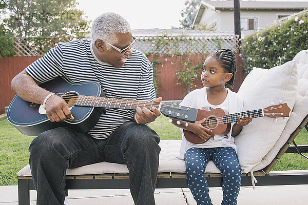 Afroamerikanischer Großvater bringt seiner Enkelin das Gitarrespielen bei