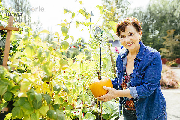 Kaukasische Frau hält Kürbis im Garten