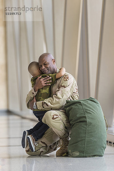 Afroamerikanischer Soldat umarmt seinen Sohn am Flughafen