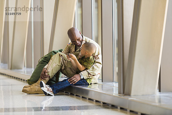 Afroamerikanischer Soldat und Sohn unterhalten sich auf dem Flughafen