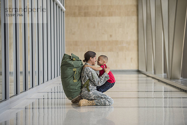 Afroamerikanischer Soldat umarmt seinen Sohn am Flughafen