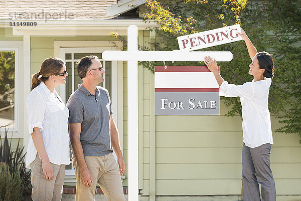 Immobilienmakler hängen Schild vor Haus