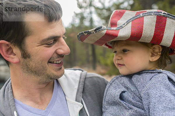 Vater trägt Tochter mit patriotischem Hut