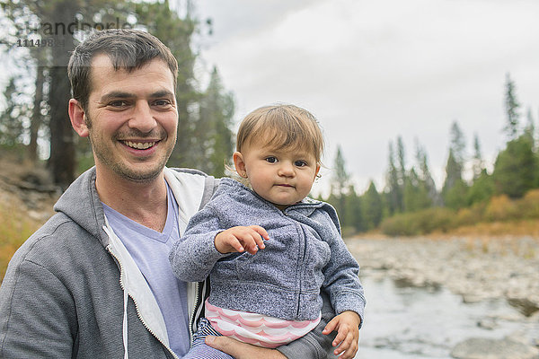 Vater trägt Tochter am Fluss