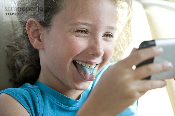 Kaukasisches Mädchen mit blauer Zunge nimmt Selfie mit Handy