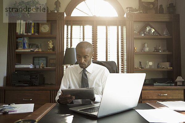 Schwarzer Arzt benutzt digitales Tablet im Büro