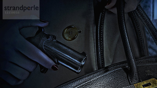 Frau steckt Waffe in Handtasche