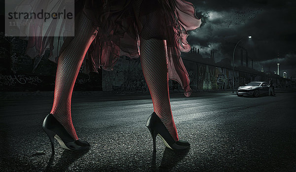 Frau mit hohen Absätzen auf der Straße bei Nacht