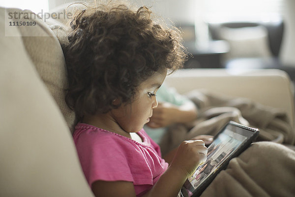 Mädchen mit digitalem Tablet auf dem Sofa