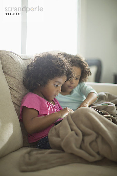 Schwestern mit digitalem Tablet auf dem Sofa