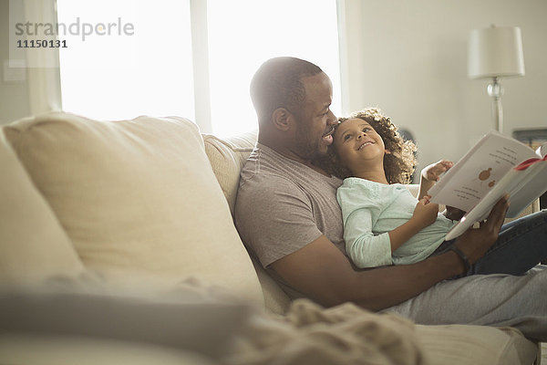Vater und Tochter lesen auf dem Sofa