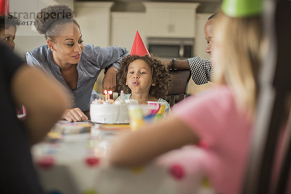 Mädchen bläst Geburtstagskerzen auf einer Party aus