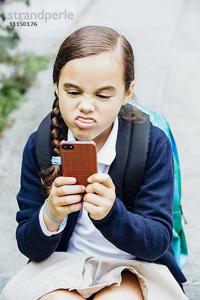 Gemischte Rasse Mädchen macht ein Gesicht auf Handy