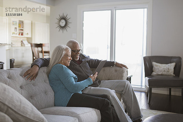 Älteres Paar benutzt digitales Tablet auf dem Sofa