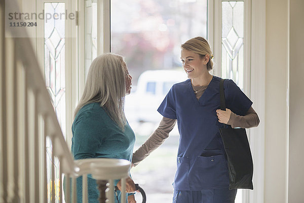 Krankenschwester im Gespräch mit dem Patienten an der Eingangstür