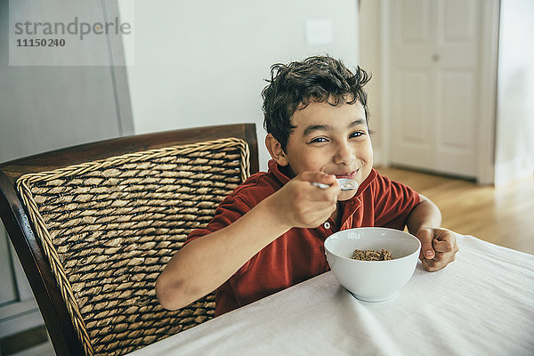 Gemischtrassiger Junge isst Müsli am Tisch