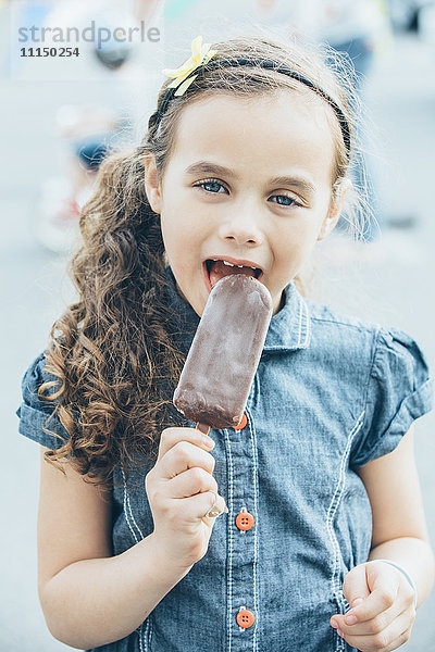 Gemischtrassiges Mädchen isst Eis am Stiel auf der Straße