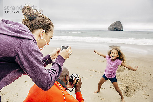 Eltern fotografieren Tochter am Strand