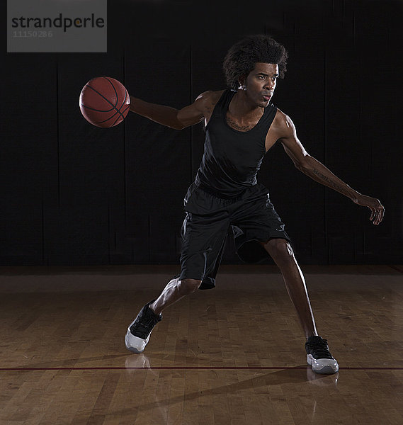 Afroamerikanischer Mann spielt Basketball auf dem Platz