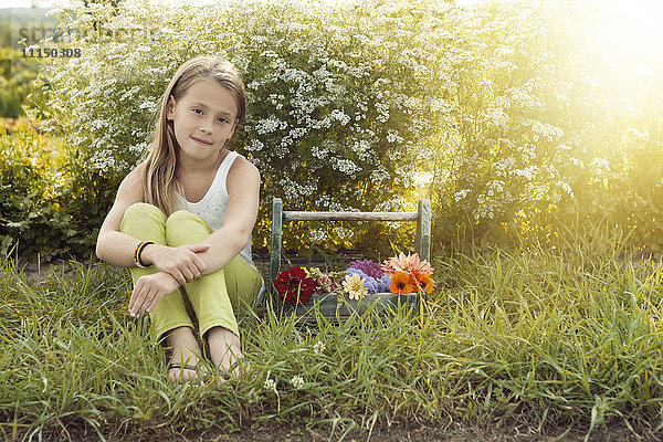 Kaukasisches Mädchen mit Blumenkorb sitzend