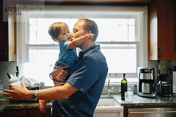 Vater küsst Babysohn in der Küche