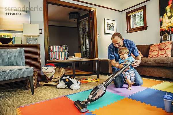 Vater und Sohn beim Staubsaugen im Wohnzimmer