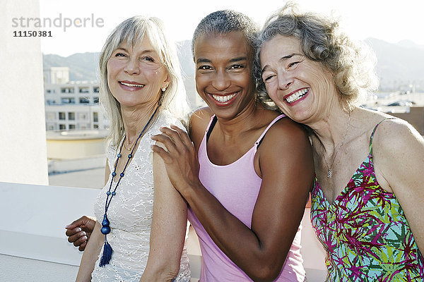 Gemeinsam lächelnde Frauen auf einem städtischen Dach