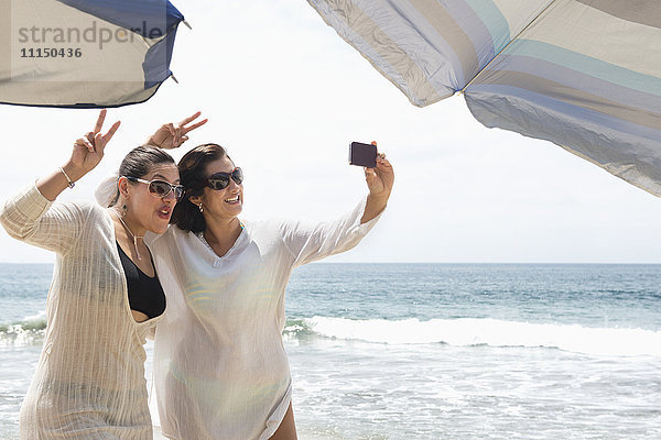 Hispanische Frauen machen Handy-Selfie am Strand