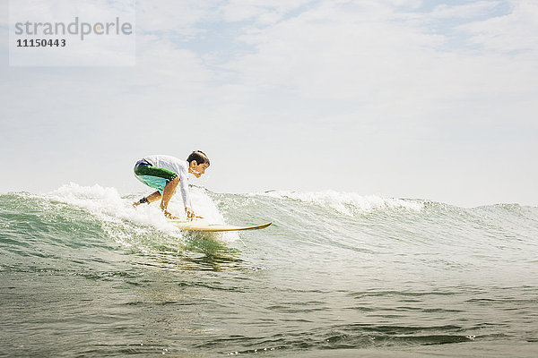 Gemischtrassiger Junge beim Surfen in den Wellen