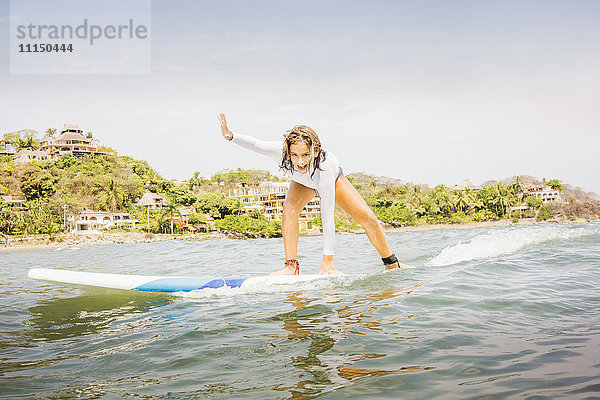 Gemischtrassiges Mädchen beim Surfen in den Wellen