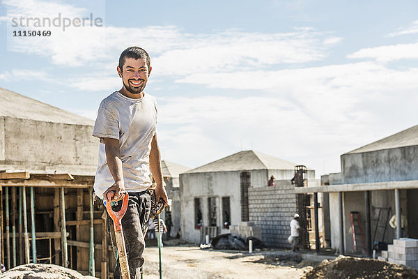 Hispanischer Bauarbeiter mit Schaufel auf einer Baustelle