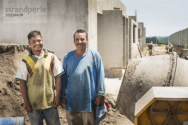 Lächelnde hispanische Bauarbeiter auf der Baustelle