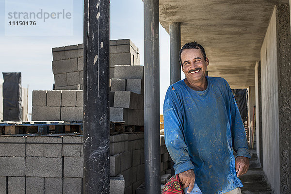 Hispanischer Bauarbeiter lächelt auf der Baustelle