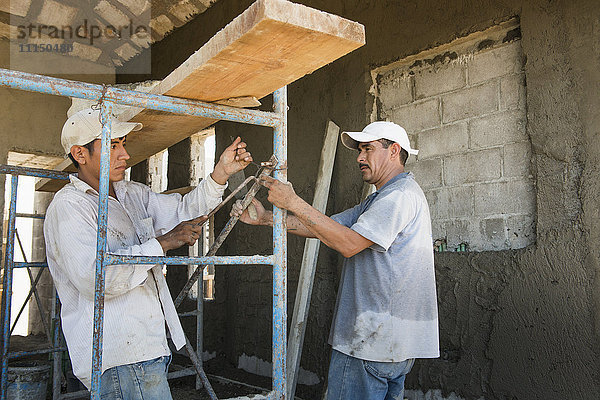 Spanische Bauarbeiter mit Baugerüst auf der Baustelle