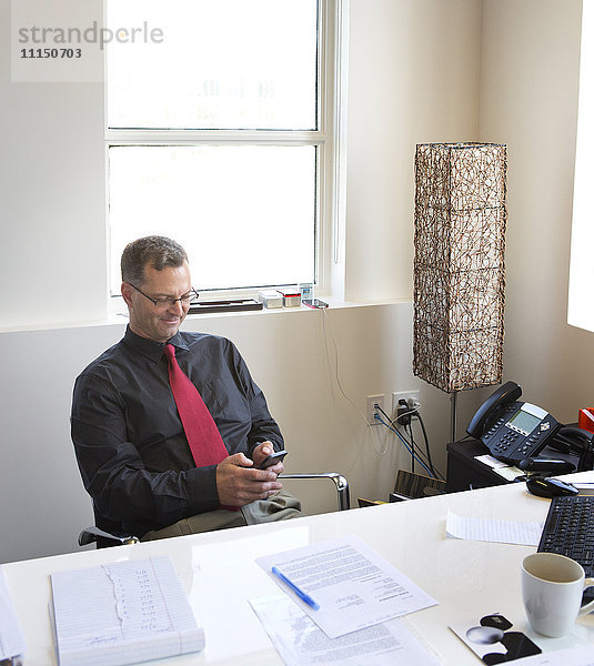 Kaukasischer Geschäftsmann benutzt Mobiltelefon im Büro