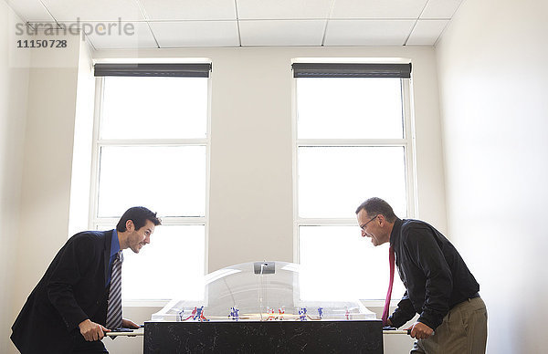 Geschäftsleute spielen zusammen im Büro Tischfußball
