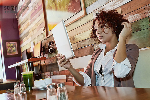 Gemischtrassige Frau benutzt Tablet-Computer in einem Café