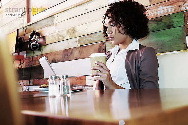 Gemischtrassige Geschäftsfrau mit Laptop in einem Cafe