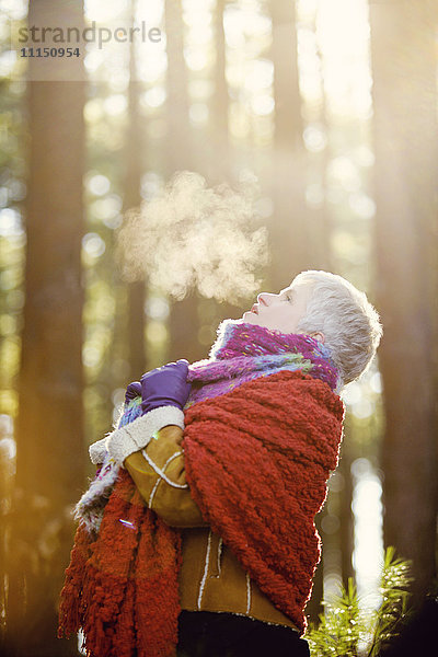 Ältere kaukasische Frau atmet Dampf im Freien