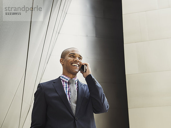 Niedriger Blickwinkel auf einen schwarzen Geschäftsmann  der mit einem Mobiltelefon spricht