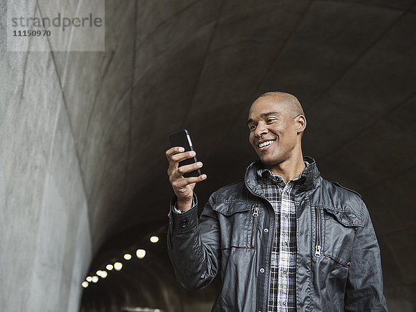 Schwarzer Mann benutzt Mobiltelefon in einem städtischen Tunnel