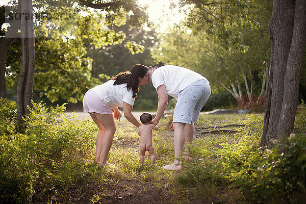 Eltern und Baby gehen im Garten spazieren