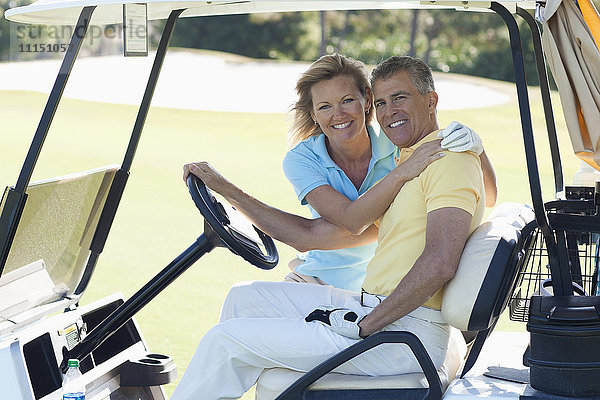 Kaukasisches Paar umarmt sich im Golfwagen auf dem Golfplatz