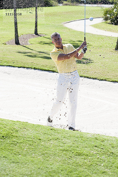 Kaukasischer Mann beim Golfen vom Sandfang auf dem Golfplatz