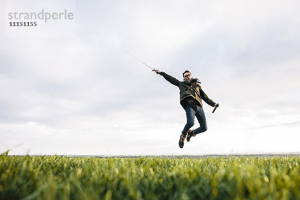 Kaukasischer Mann  der sein Schwert auf einem Feld auszieht