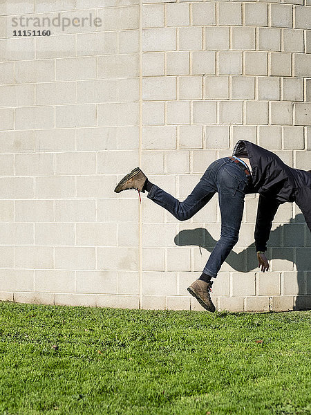 Kaukasischer Mann fällt in der Nähe einer Mauer