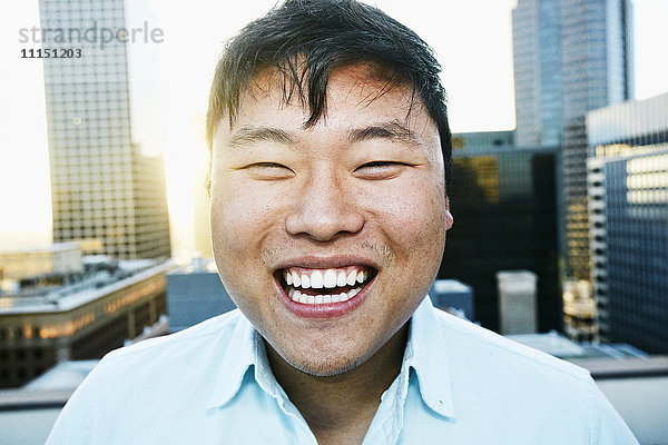 Koreanischer Mann lächelnd auf dem Dach einer Stadt